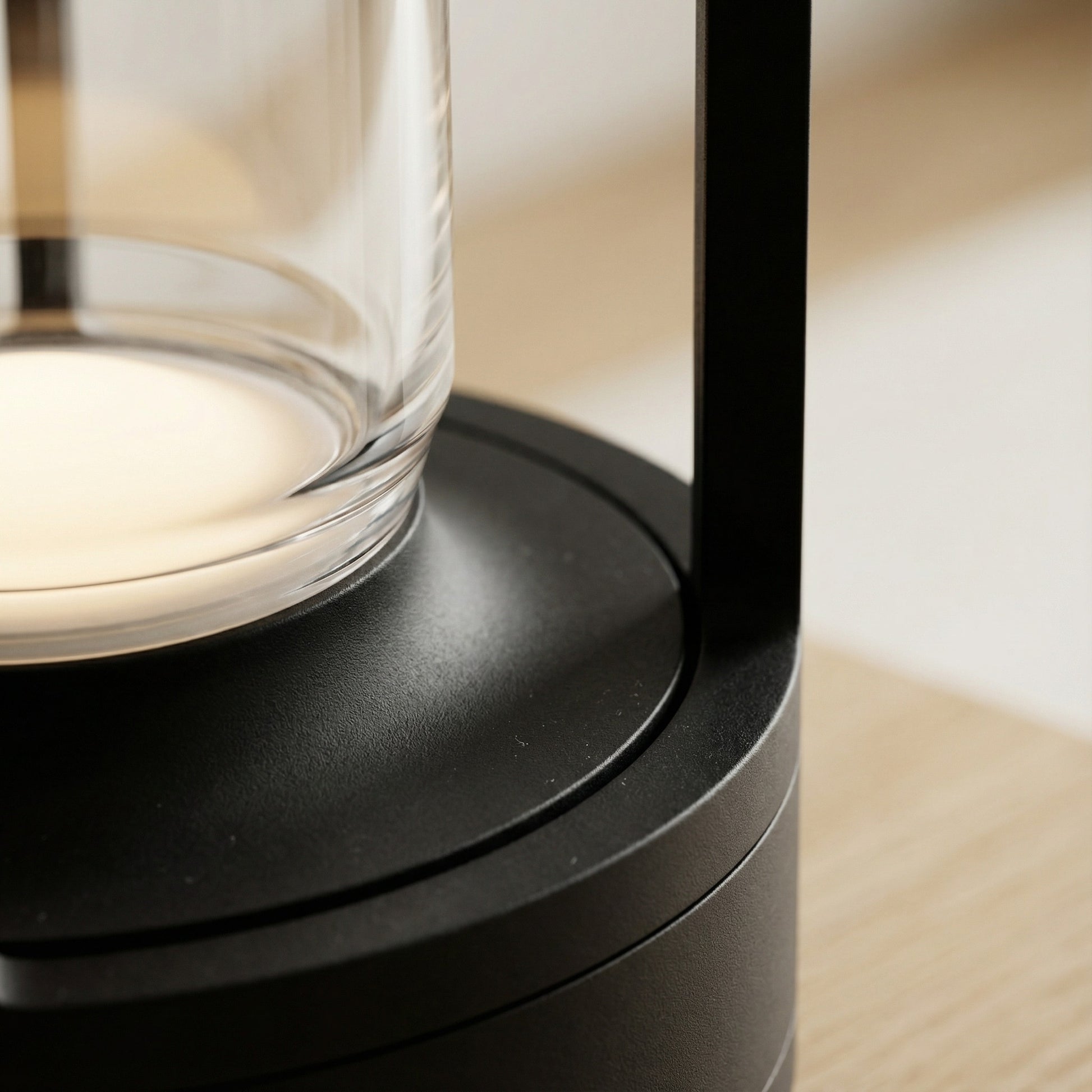 Close-up of a modern black lamp with a glass shade on a wooden surface.