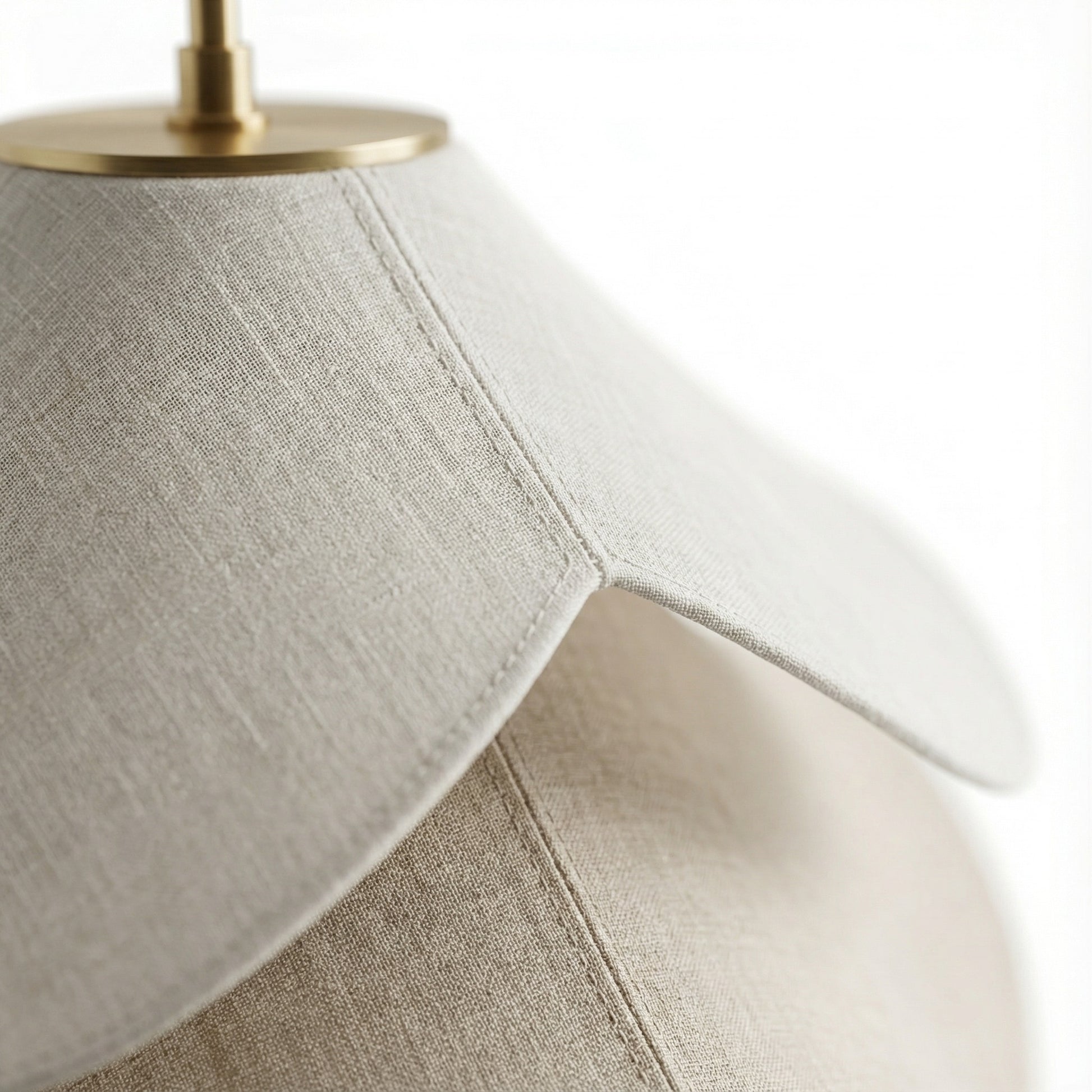 Close-up of a lamp with a textured beige shade and brass fixture on a white background