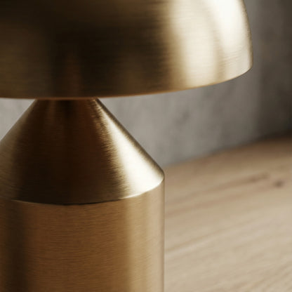 Close-up of a gold lamp on a wooden surface with a blurred background