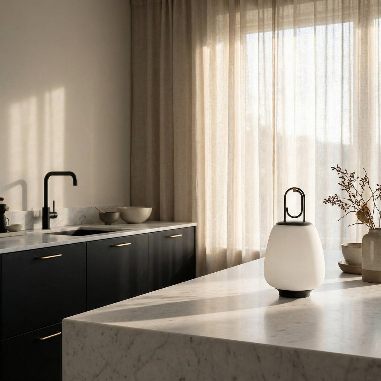 Modern kitchen with marble island, black cabinets, and large window with sheer curtains.