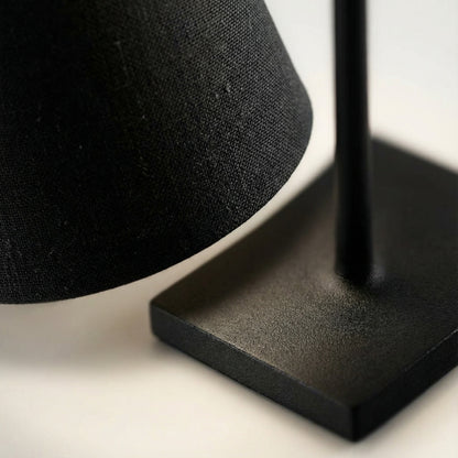 Close-up of a black lampshade on a stand with a blurred background