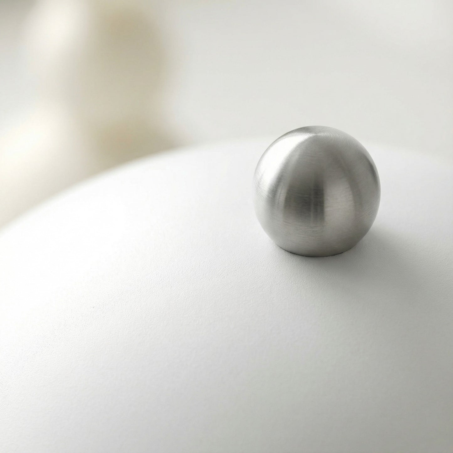 Metallic sphere on a reflective surface with a blurred background