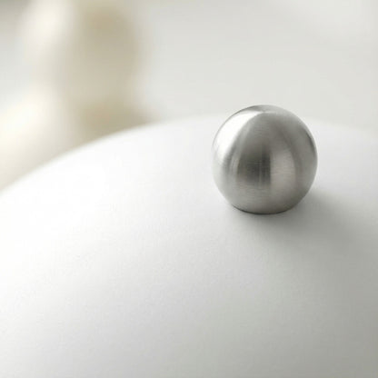 Metallic sphere on a reflective surface with a blurred background