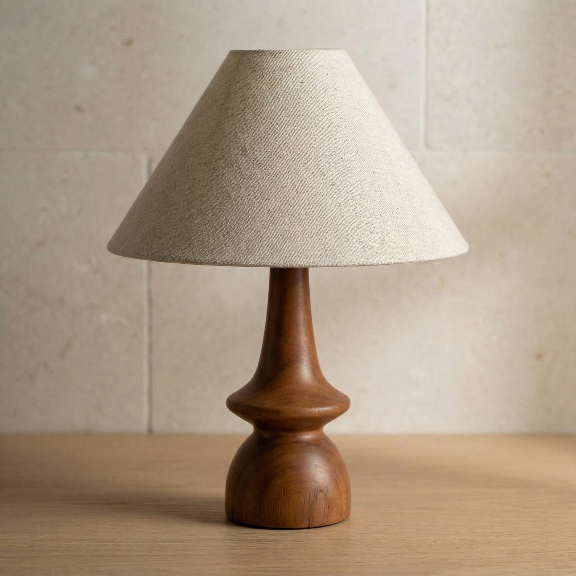 Table lamp with wooden base and beige fabric shade on a wooden surface.