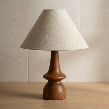 Table lamp with wooden base and beige fabric shade on a wooden surface.