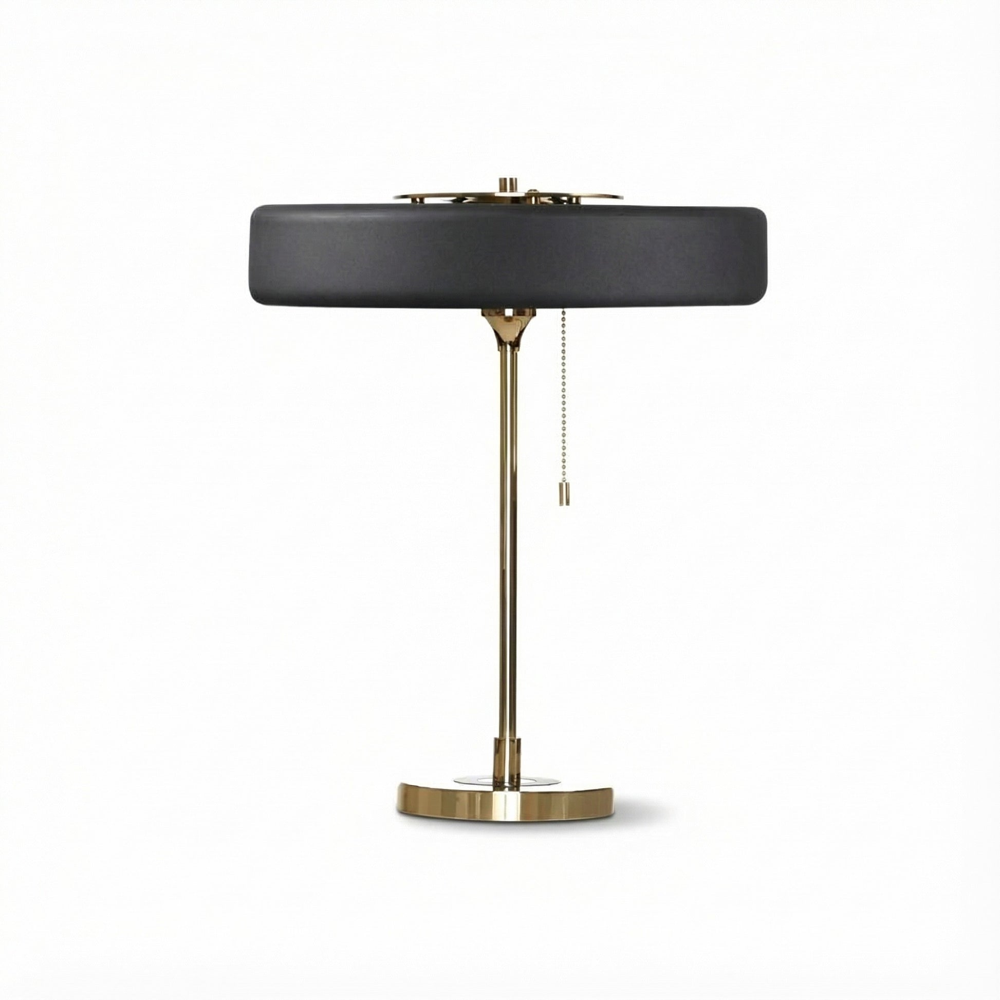 Table lamp with black shade and brass base on a white background