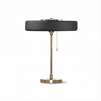 Table lamp with black shade and brass base on a white background